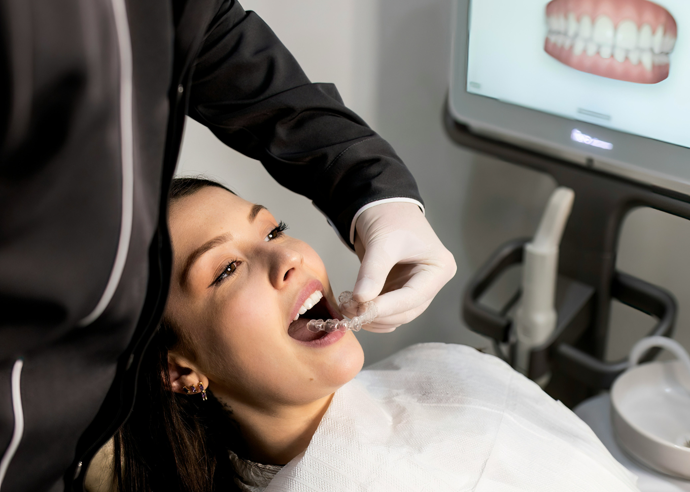 Dentista poniendo ortodoncia invisible a paciente en consulta